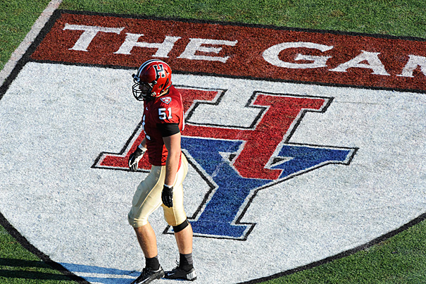 A football player standing on a logo of the Harvard/Yale Game