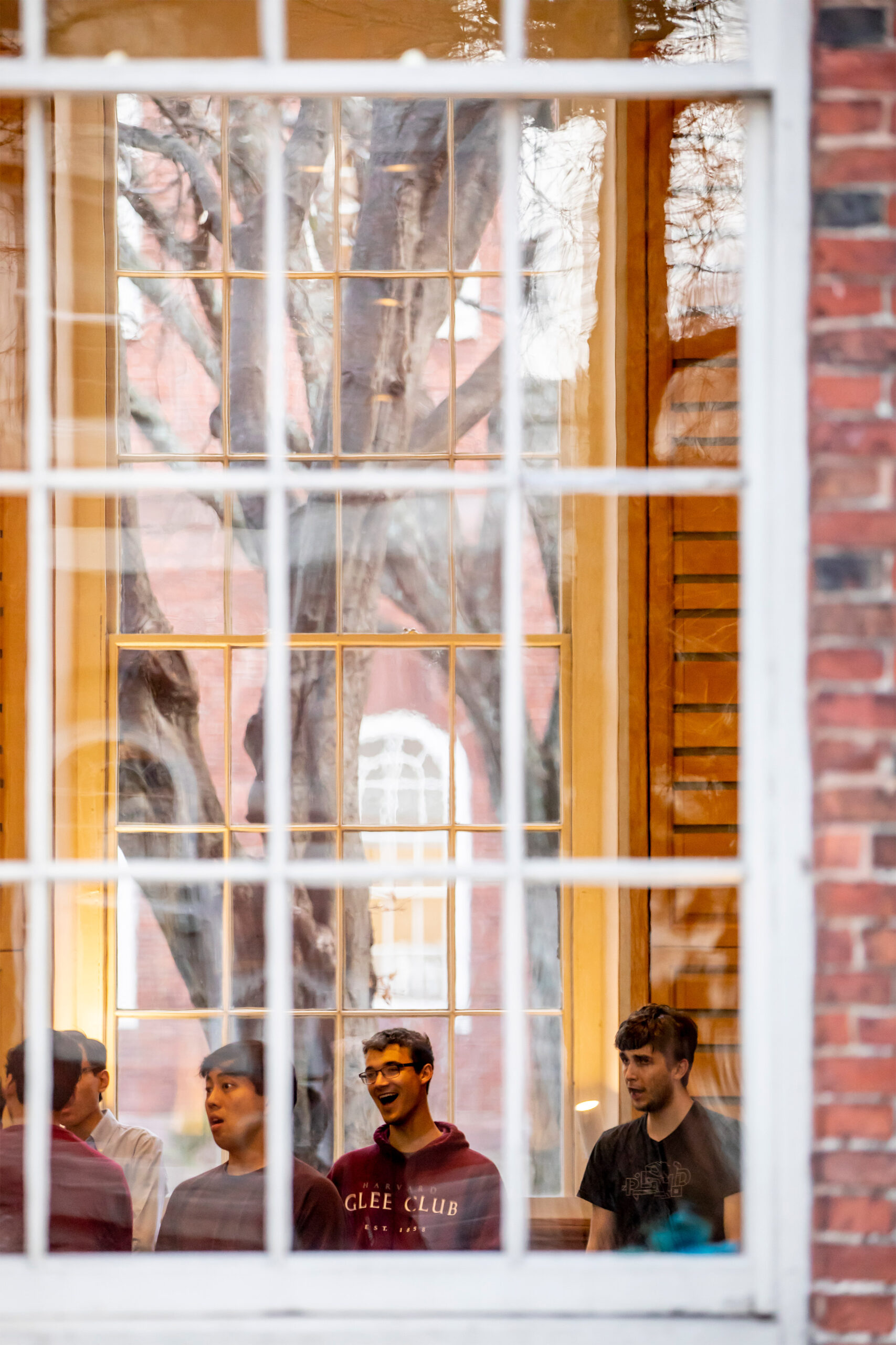 Through a window, the Harvard Glee Club rehearses.