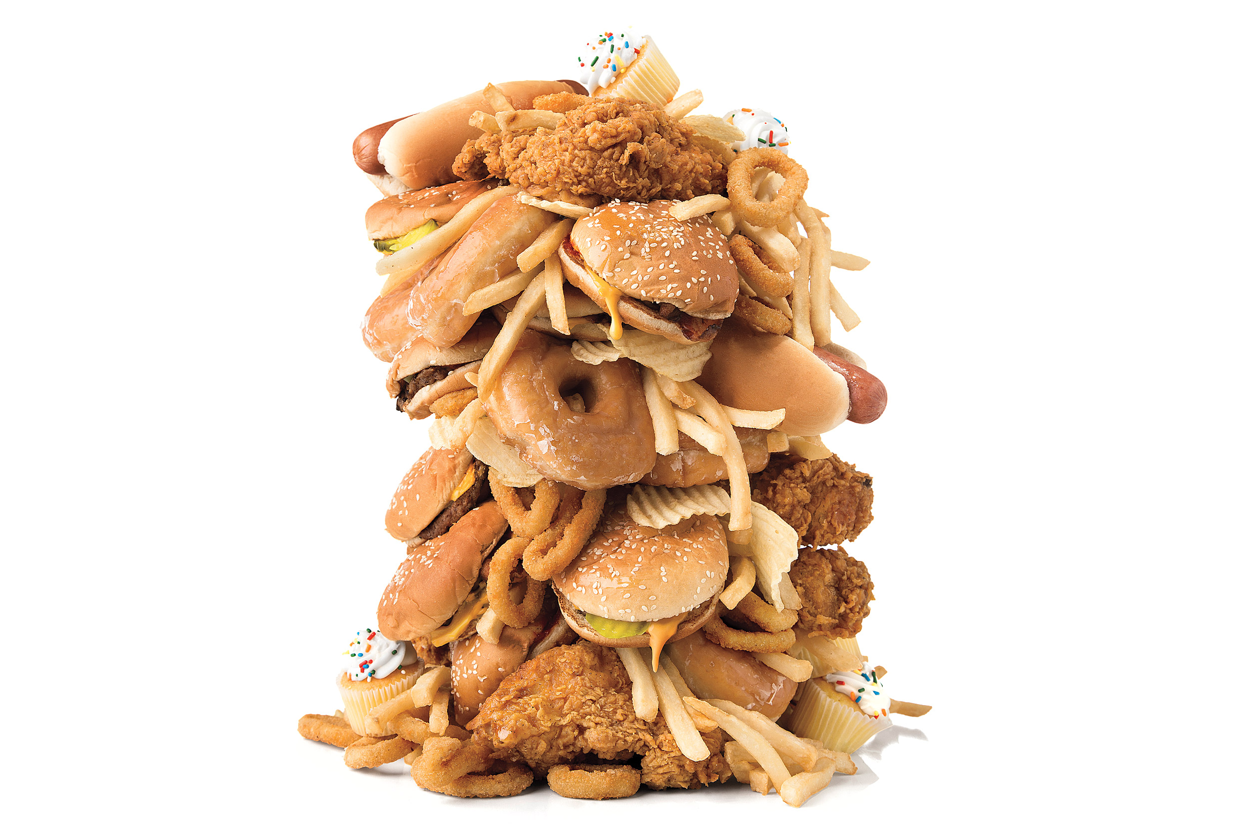 A tower of junk food including fried chicken, hamburgers, hot dogs, french fries, and cupcakes.