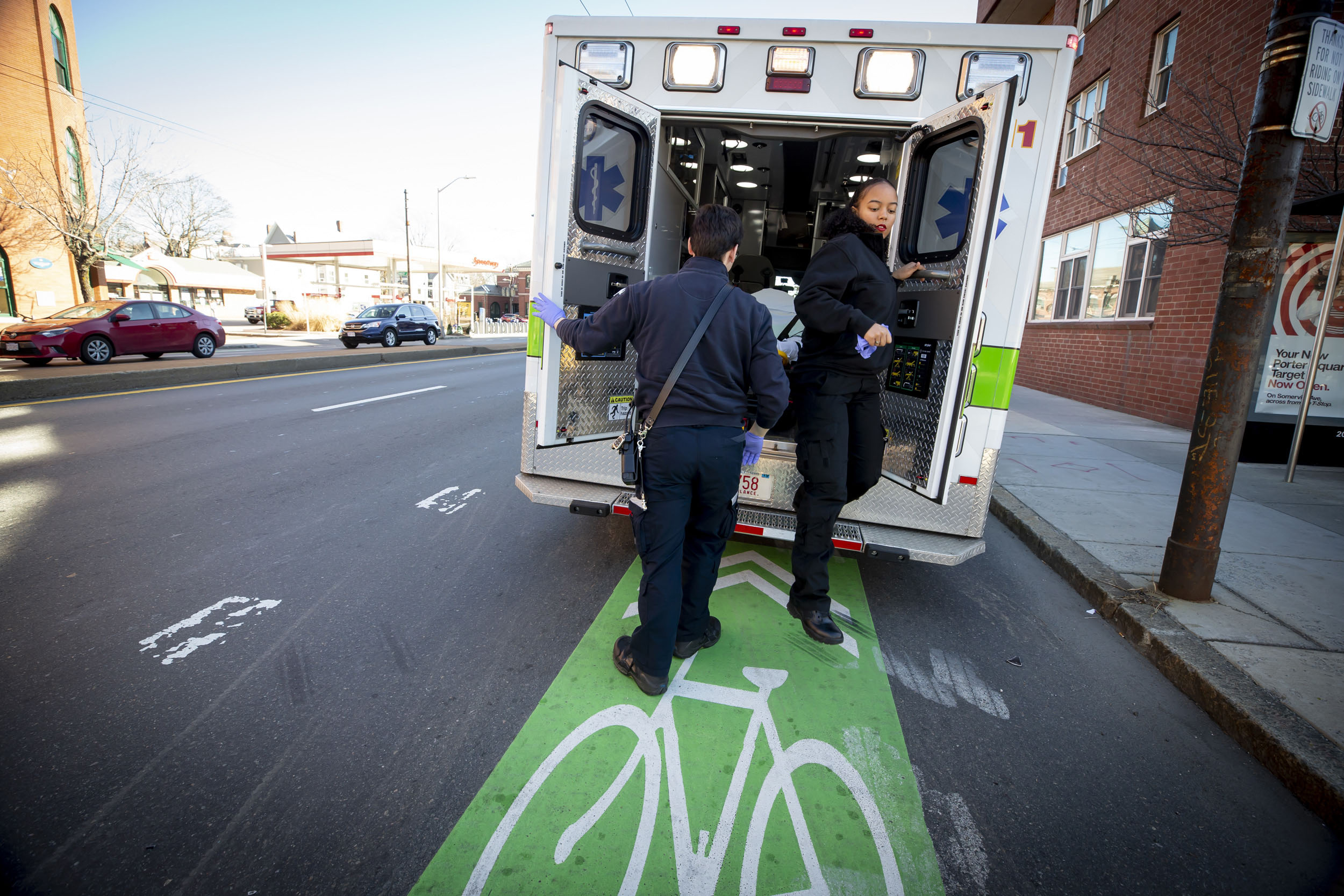 EMTs exit the back of an ambulance parked on the street.