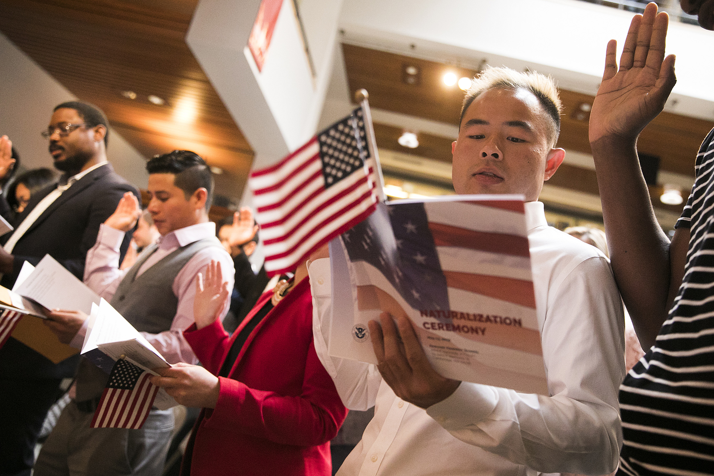 Man holding American flag reading from a booklet at a ceremony