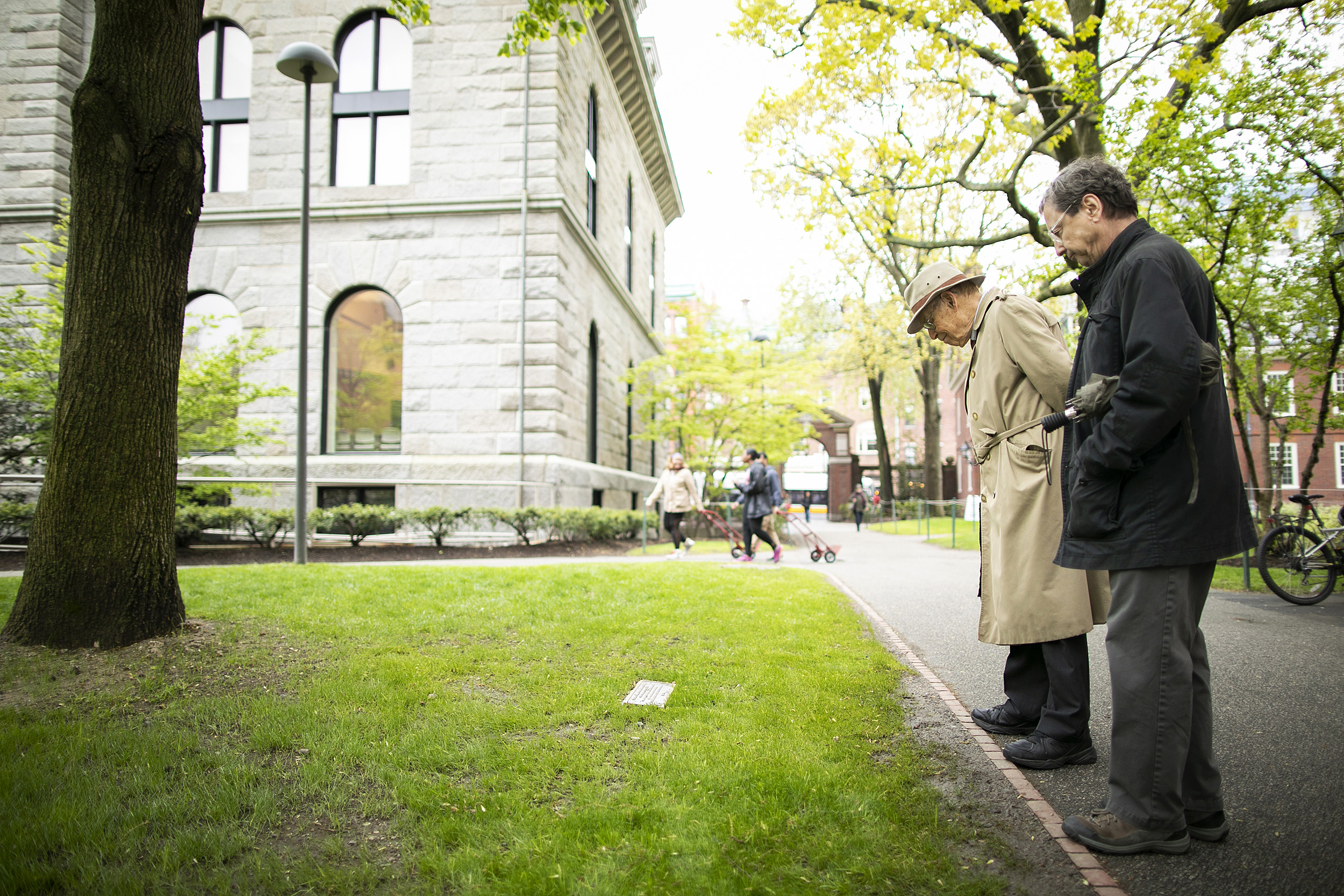 Two men examine plaque in Harvard Yard.