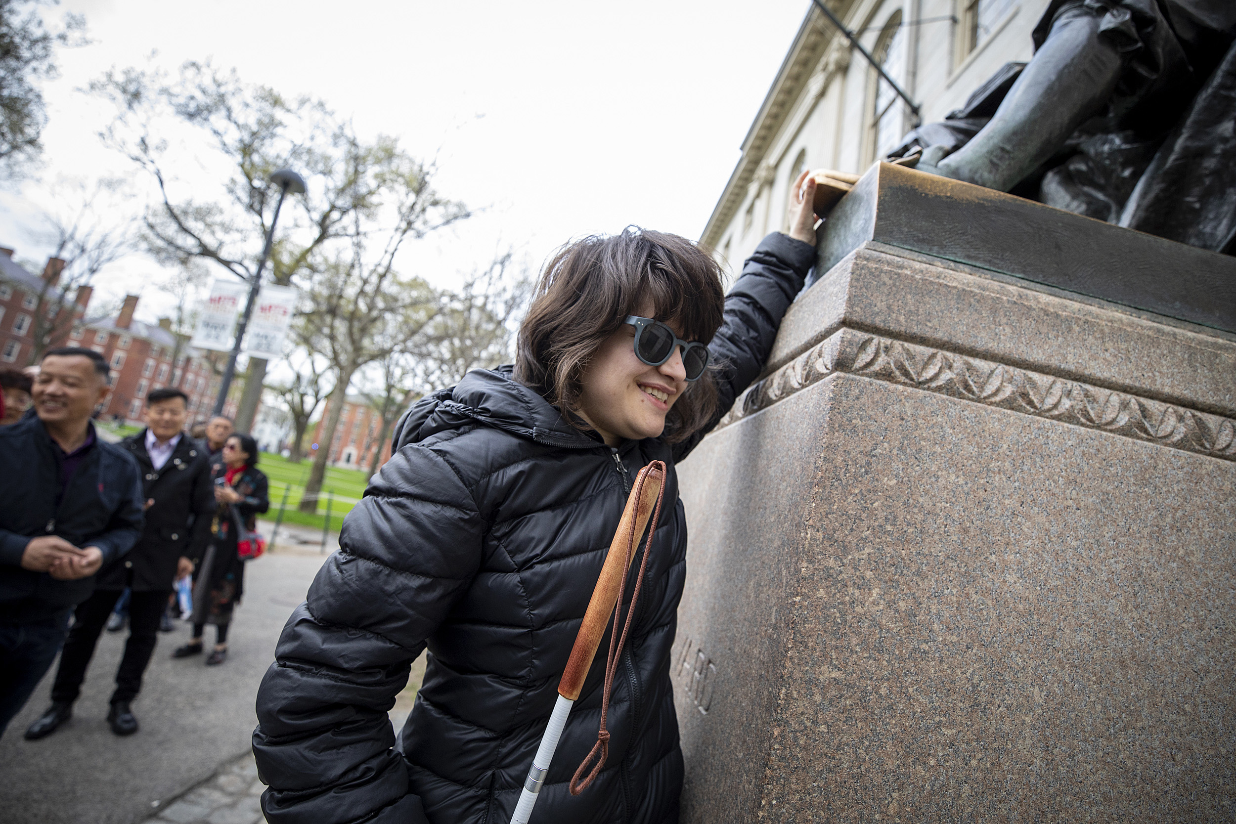 Jordan Scheffer touches the John Harvard statue.