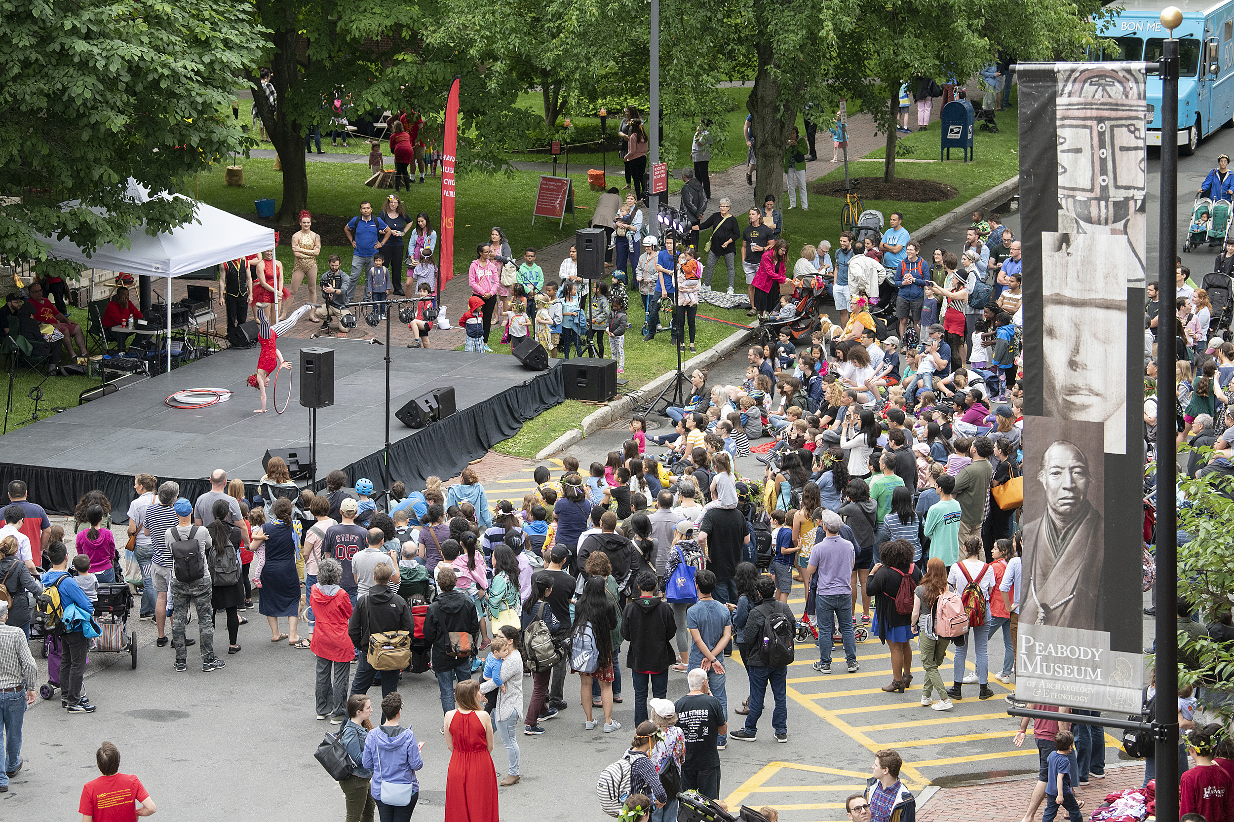Crowd gathers around and outdoor stage to watch circus performers