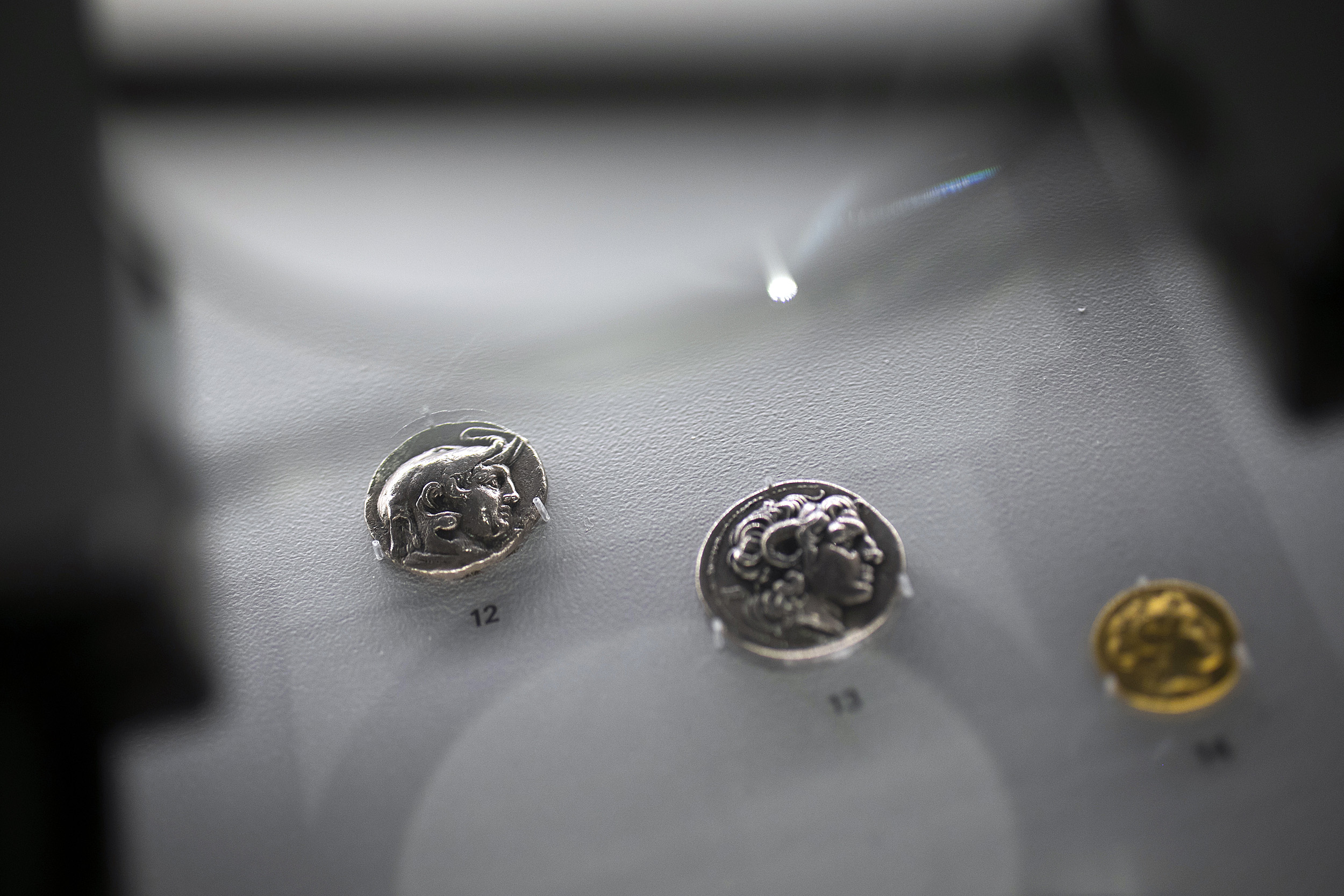 three ancient coins in a display case