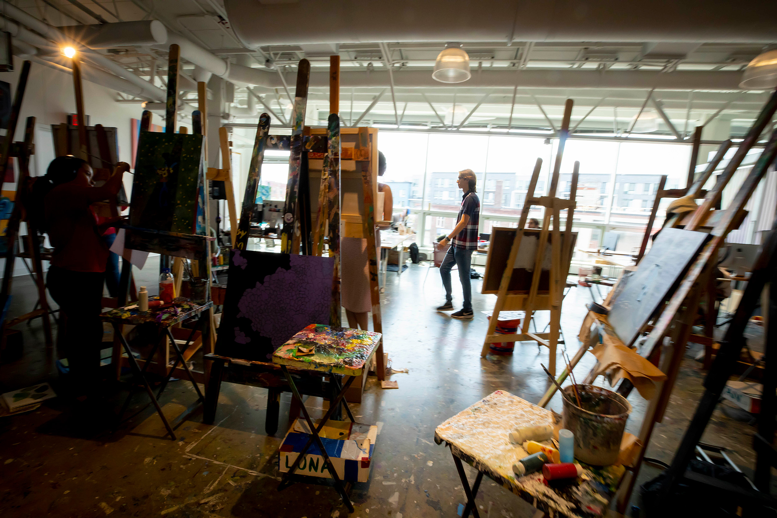 Student walking through easels in an art room.