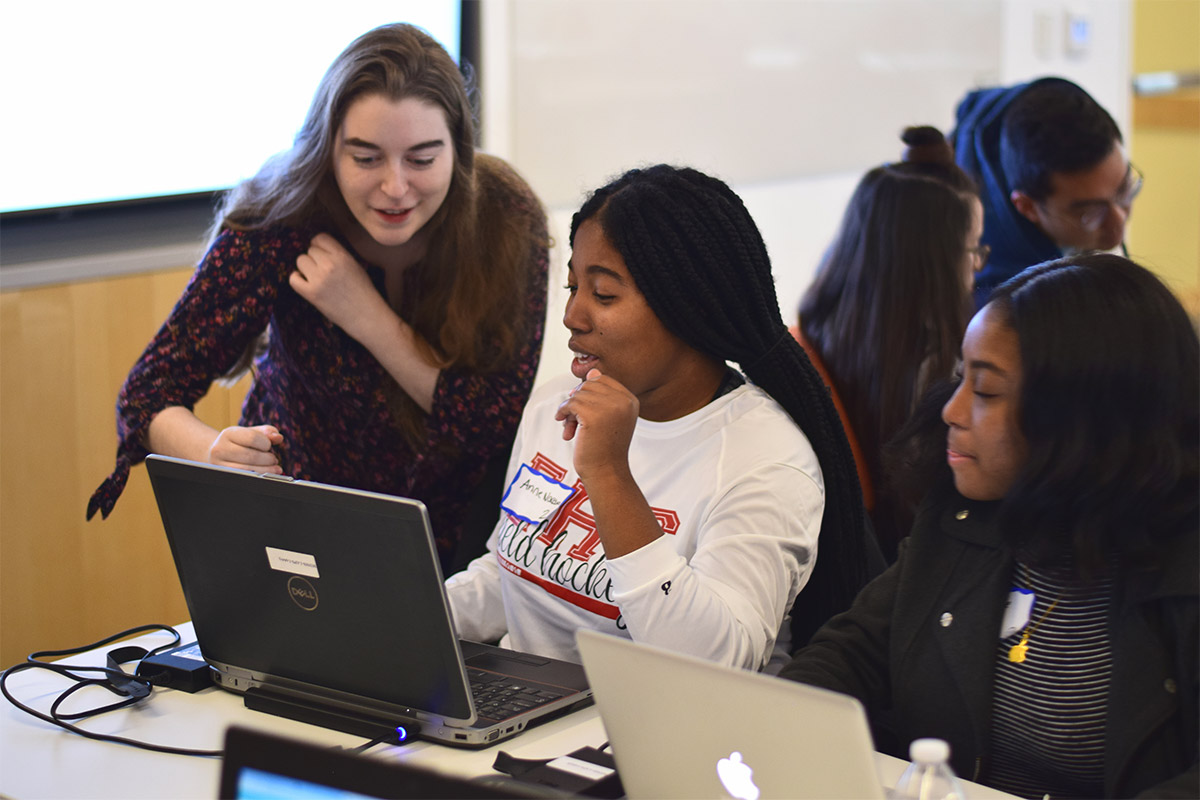 two students working at a laptop while an instructor points something out