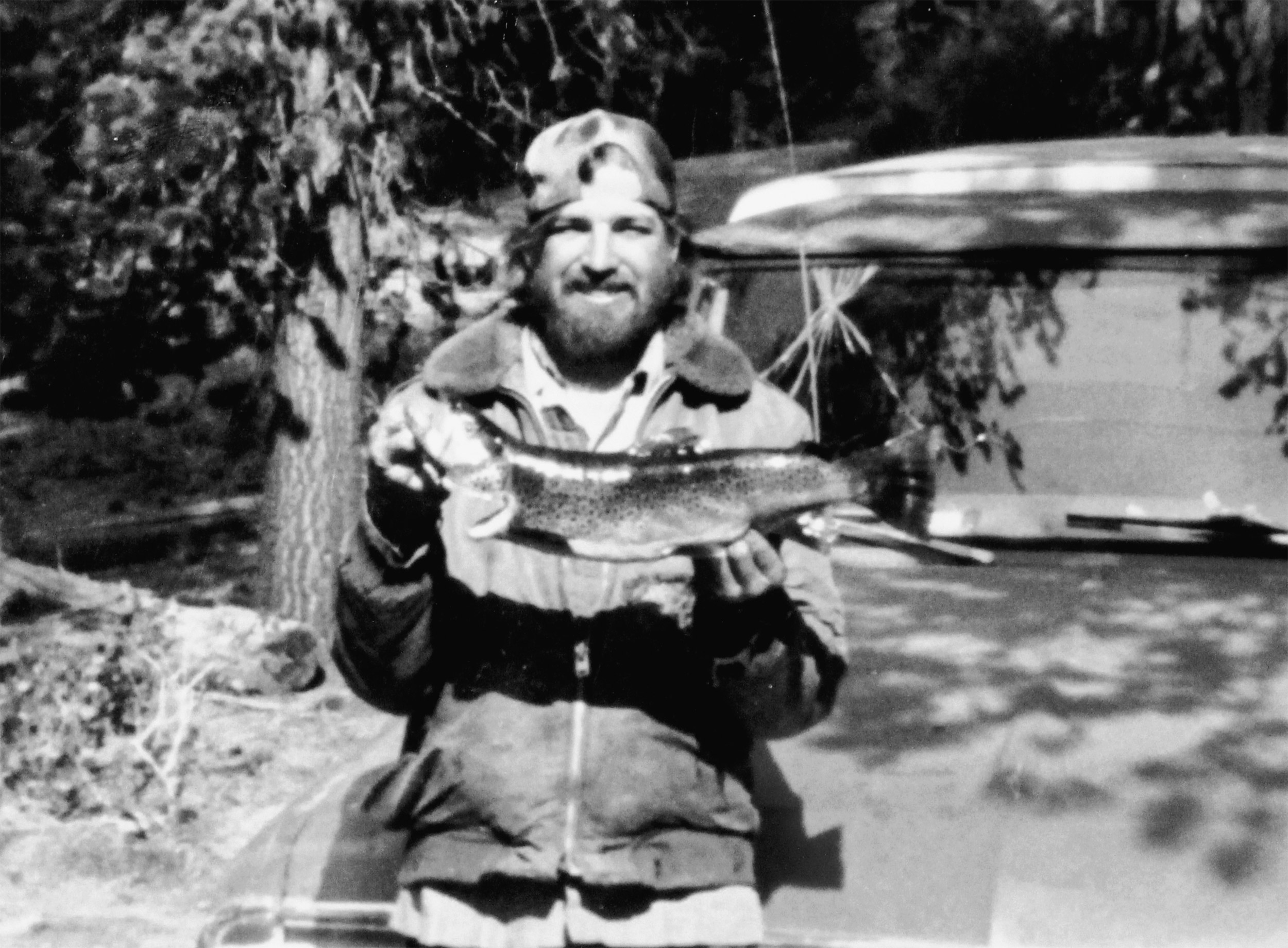 Bearded man holding large trout.