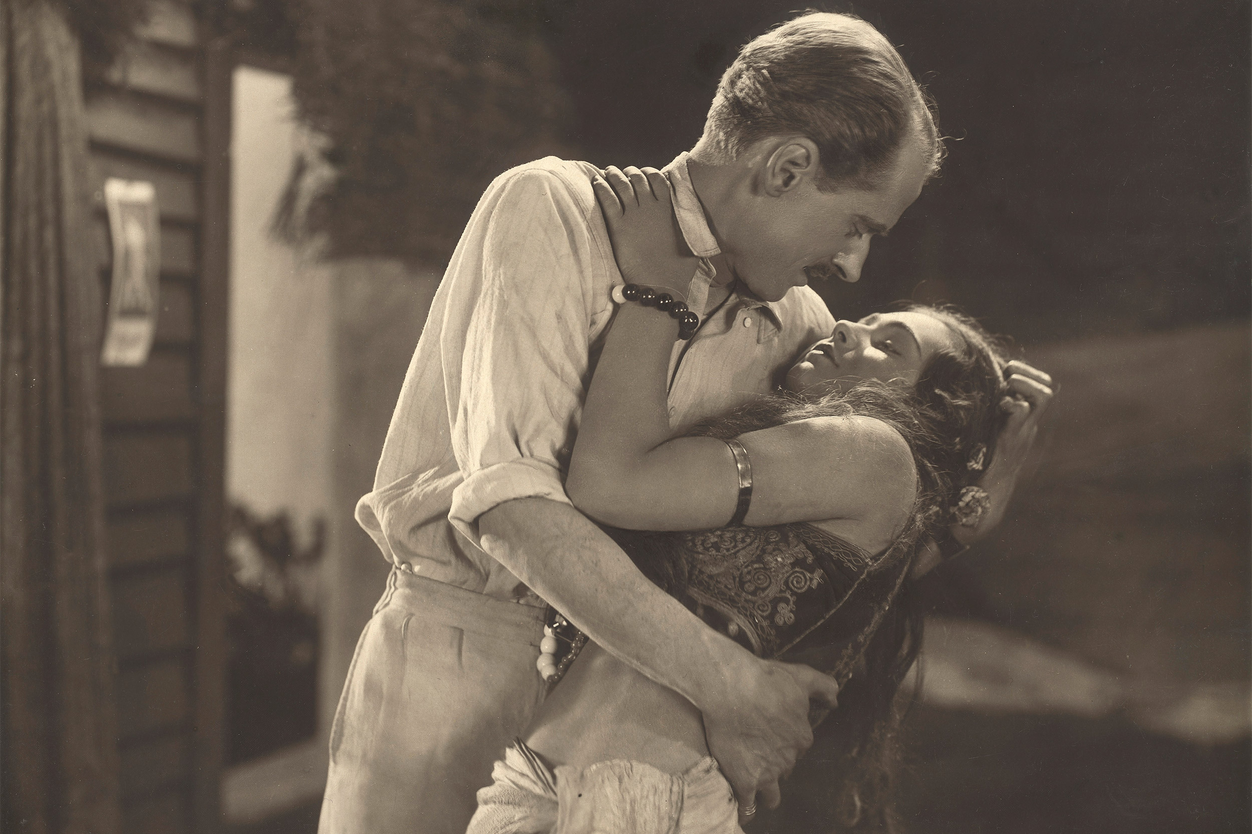 Man embracing woman in still from "The Pleasure Garden."