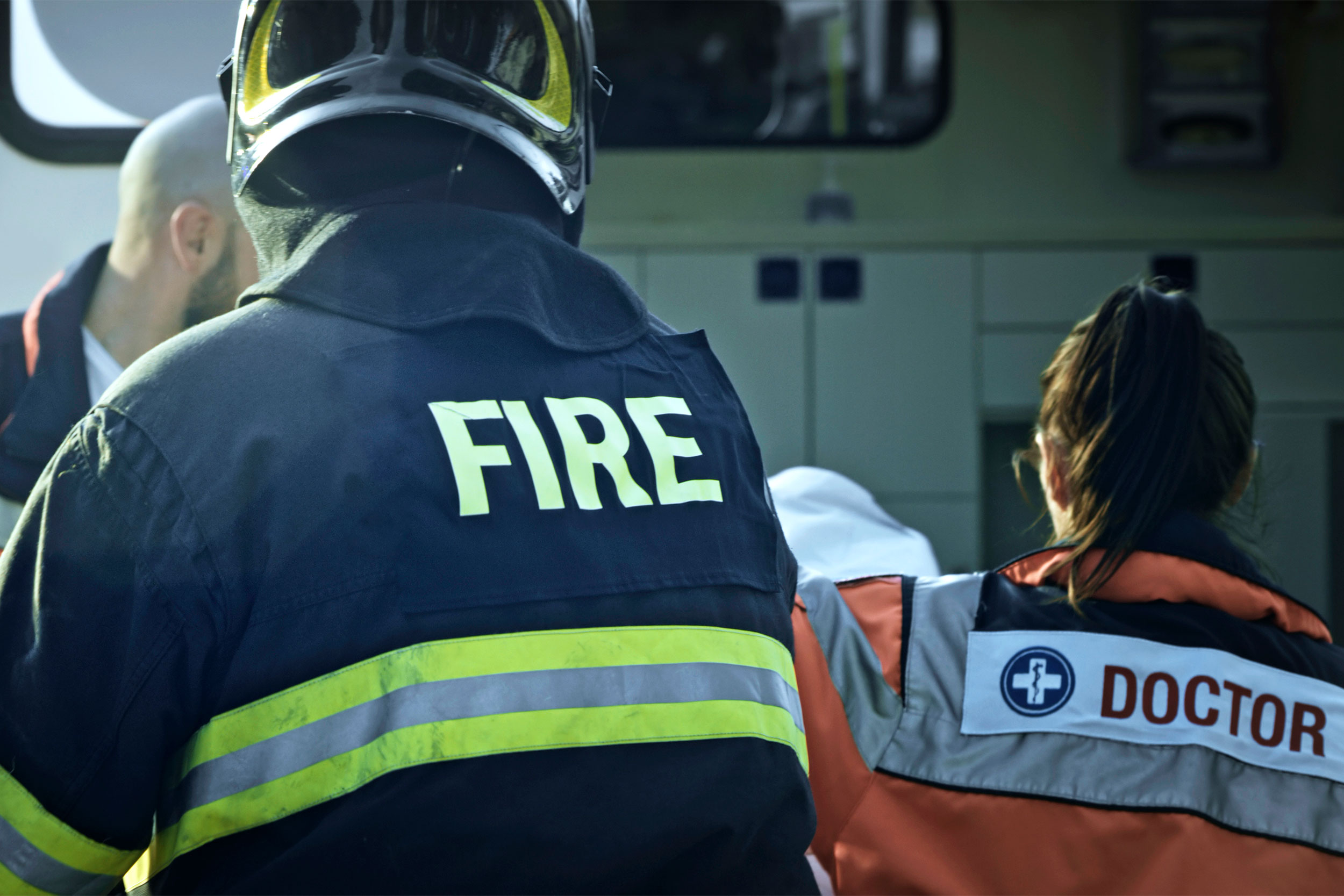 Fireman, EMT and doctor next to ambulance.