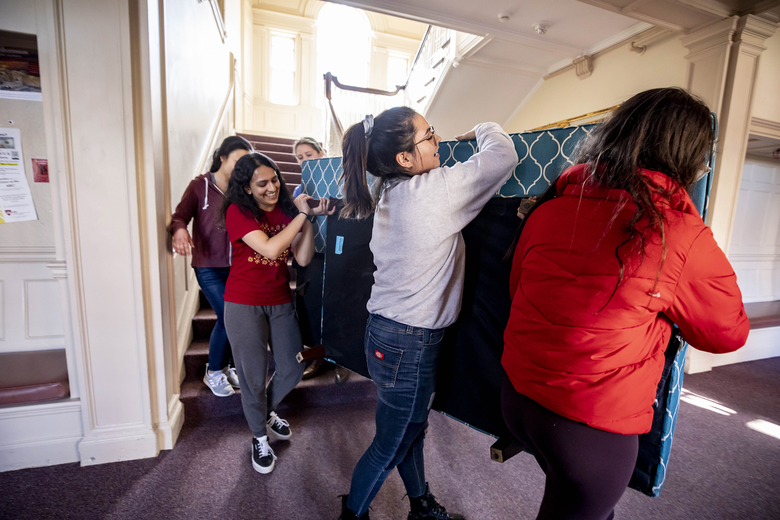 Roomates carrying out a mattress.