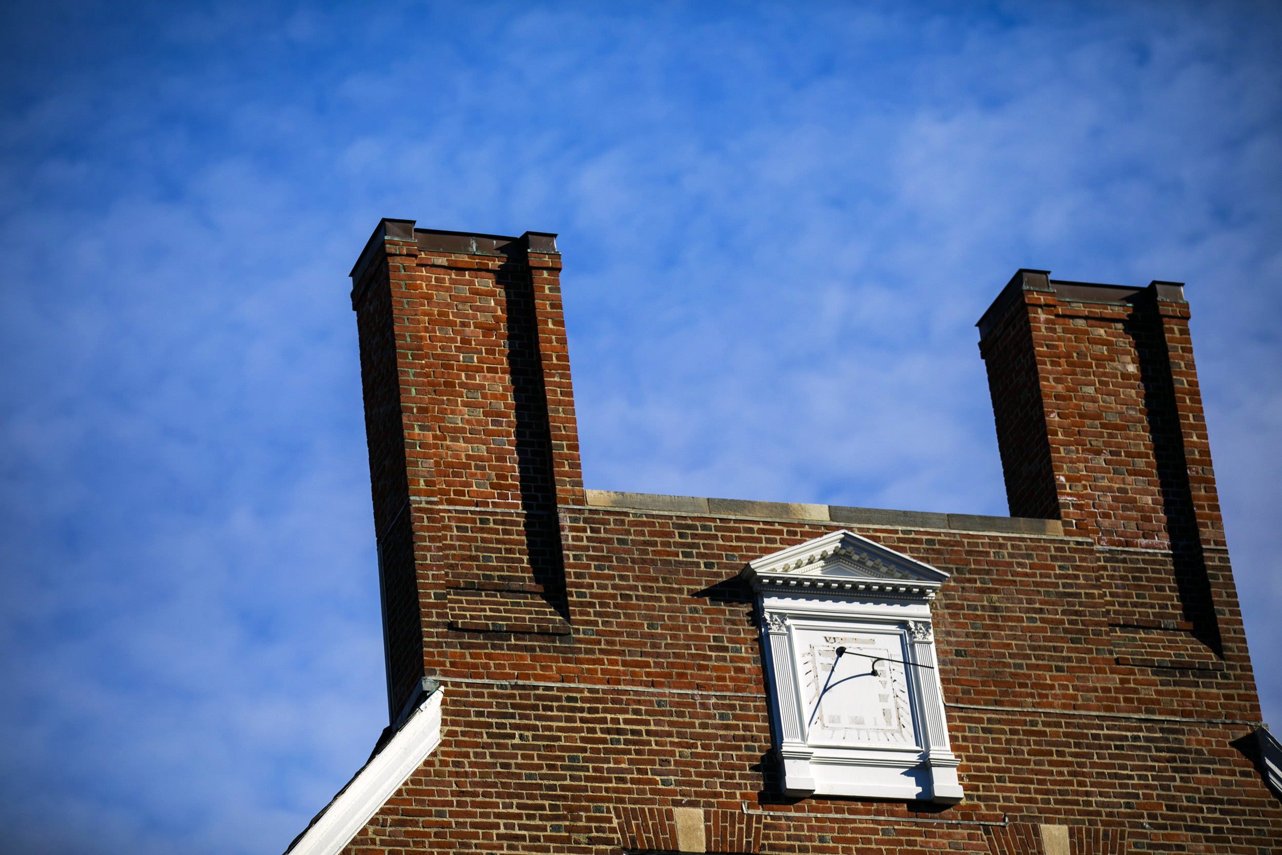 A twin-chimneyed gable connected by a horizontal parapet bridge is pictured at Kirkland House.