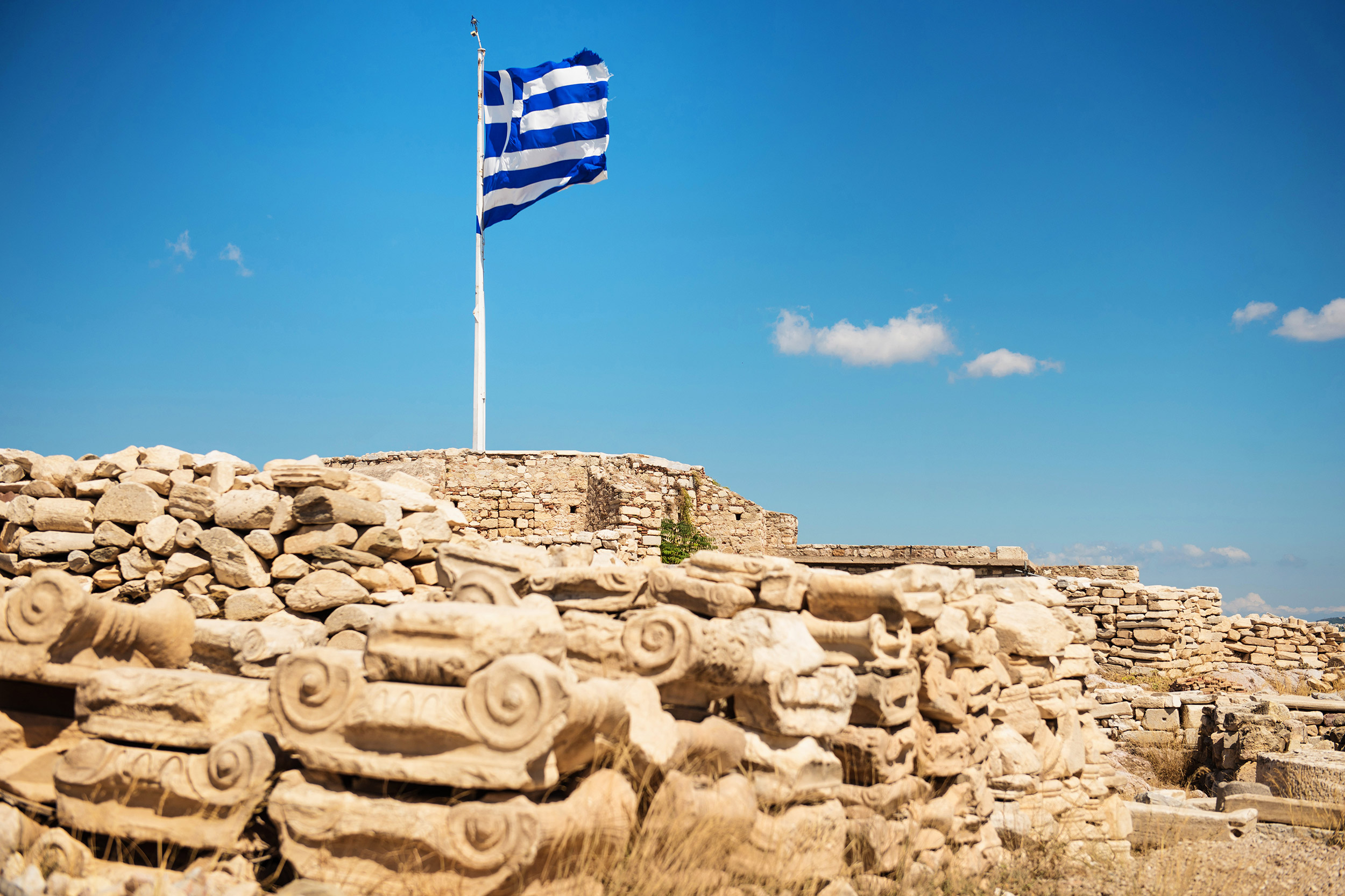 Waving flag of Greece on the top of the Acropolis Hill in Athens.