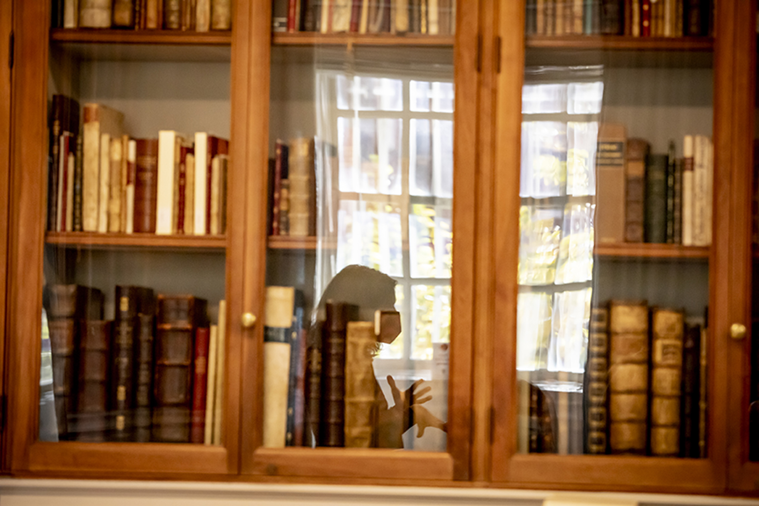 Irene Peirano Garrison reflected in bookcase.