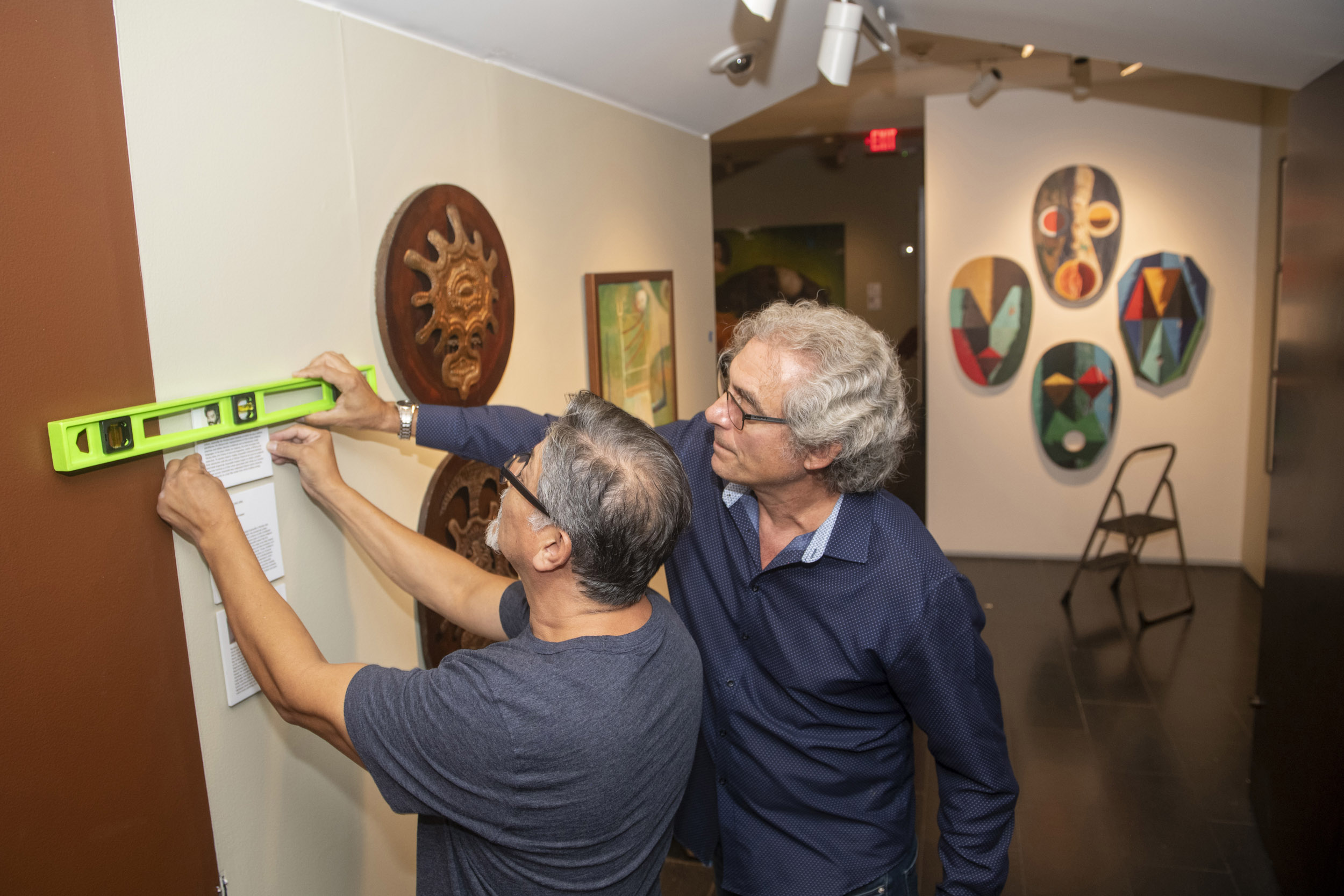 Alejandro de la Fuente and Pablo Gonzalez hang exhibition labels.