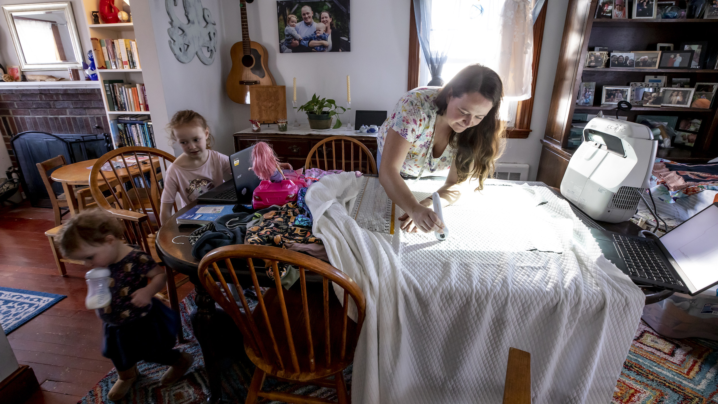 Kate Pease with daughters Ella and Coraline works on fabric arts in her dining room.