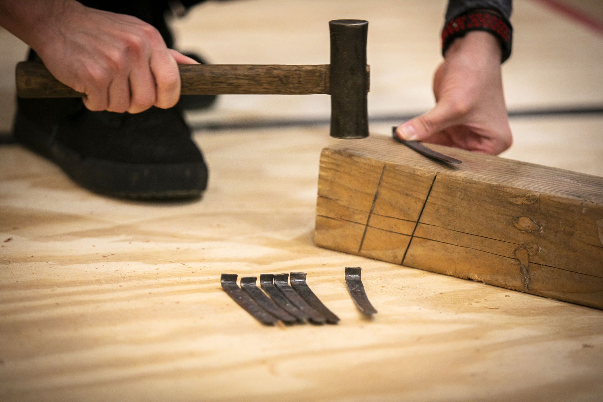 Hensch hammers a slight bend into a flat steel nail handcrafted by a blacksmith.