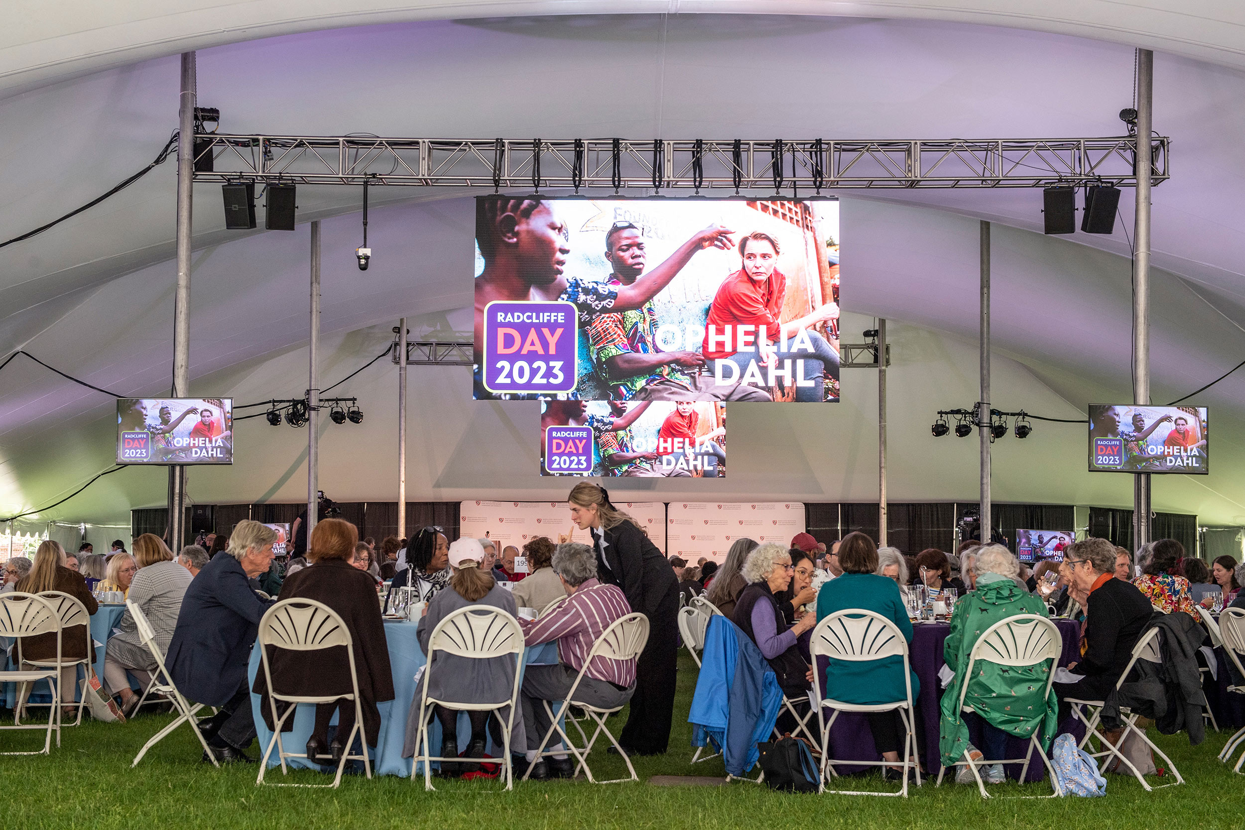 Guests sit at tables under a tent in Radcliffe Yard.