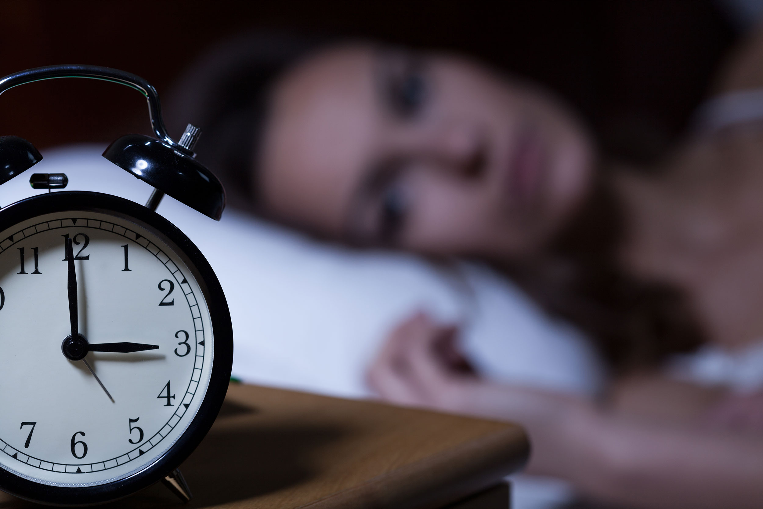 Woman not sleeping with clock showing 3 a.m.