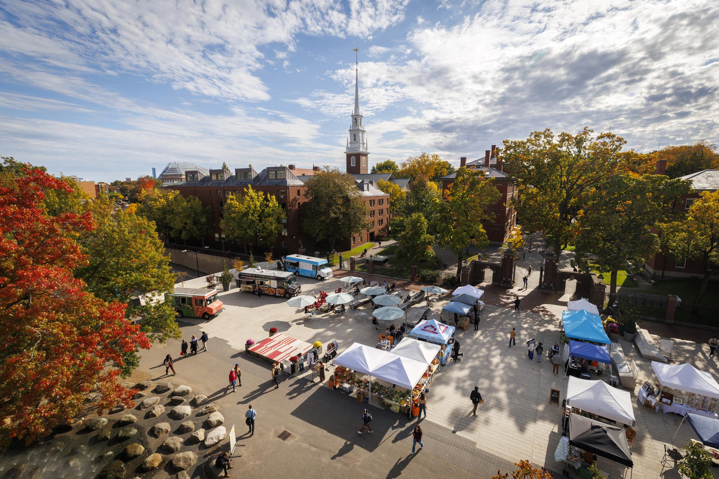 An overview shows vendors selling seasonal fruits and vegetables at the weekly farmers market on Science Center Plaza.