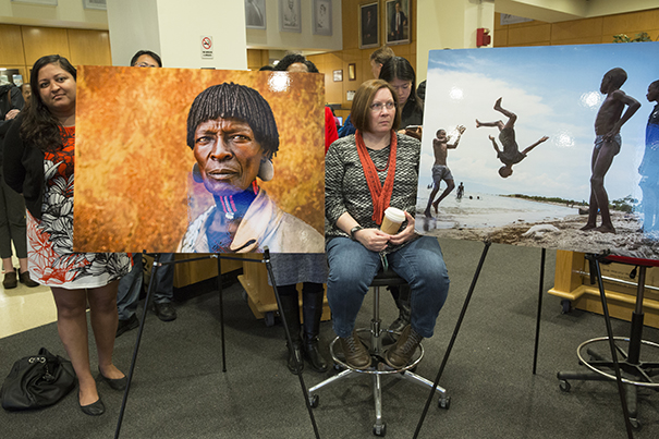 Framed by large photos set up for the event, Summon Chaudhury, left, and Julie Rioux attend the global health forum at the T.H. Chan School.