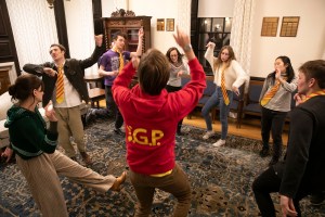 Students in a circle strike poses to practice their improv techniques.