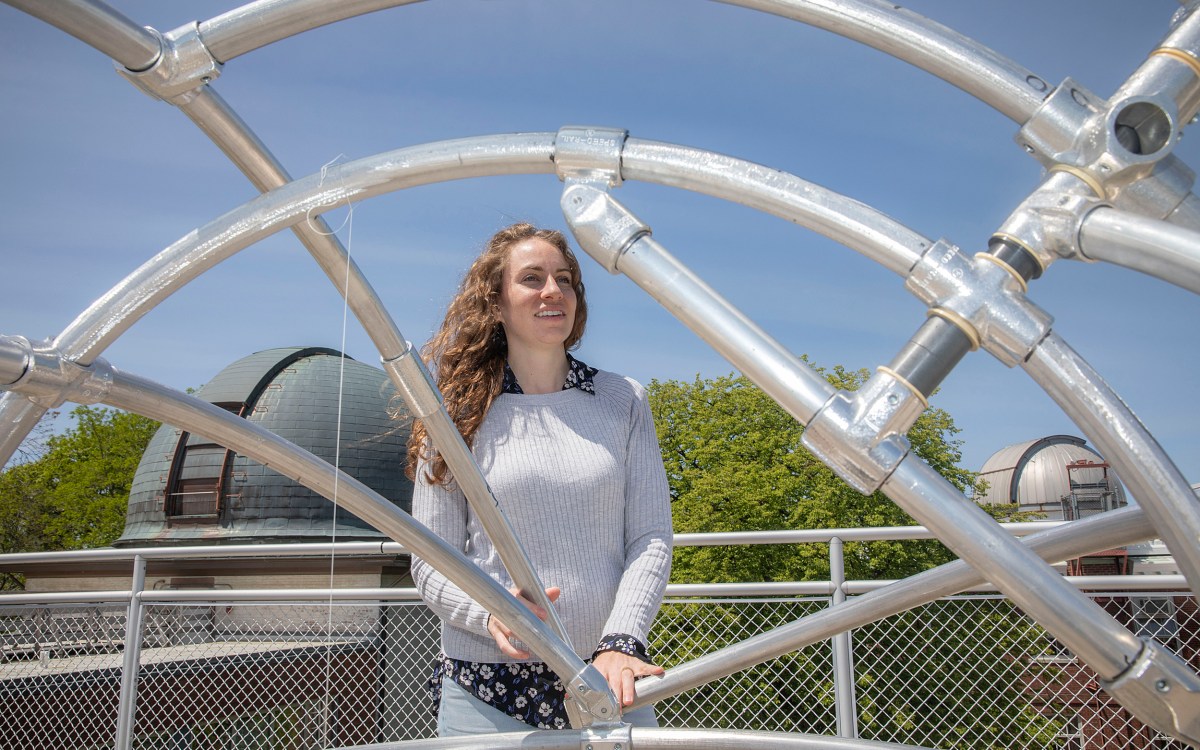 Center for Astrophysics astronomer Laura Kreidberg framed by a metal structure