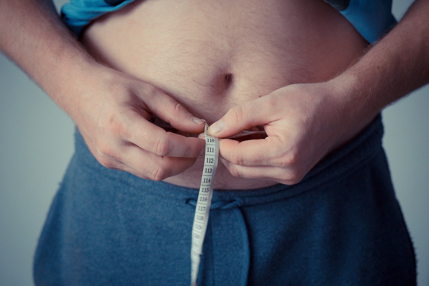 person measuring their waist with a measuring tape