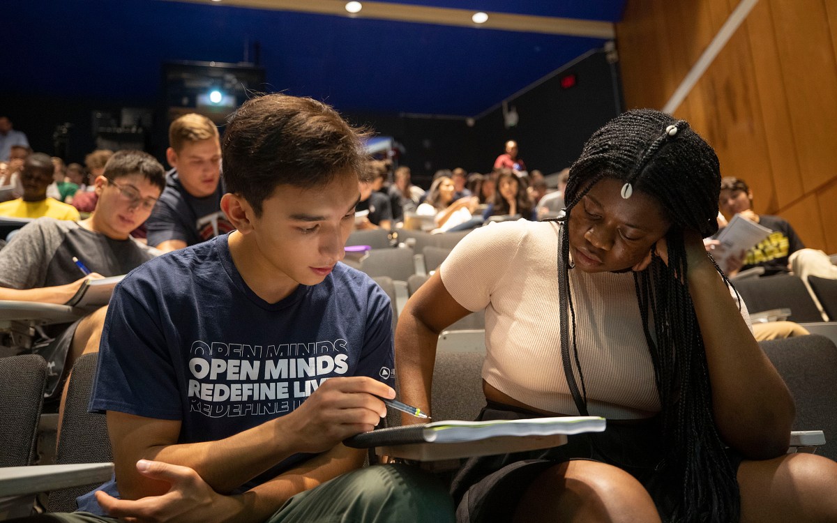 two students looking at notebook together