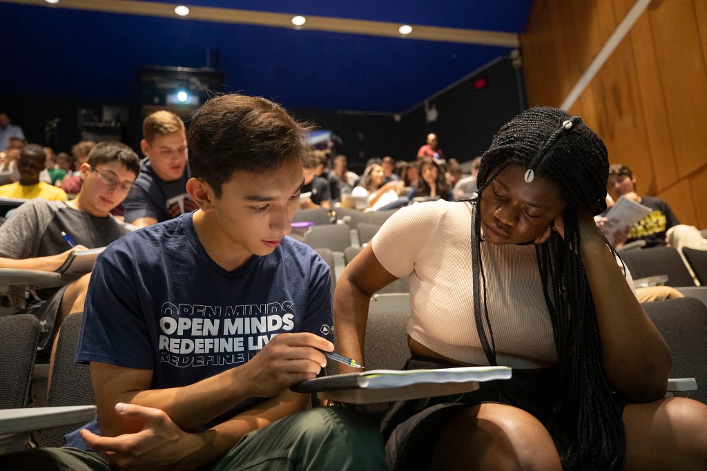 two students looking at notebook together