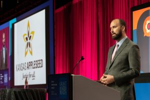 Benet speaking at a podium