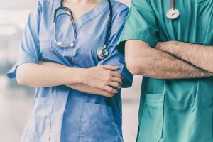 Two people standing next to each other in hospital scrubs with arms crossed