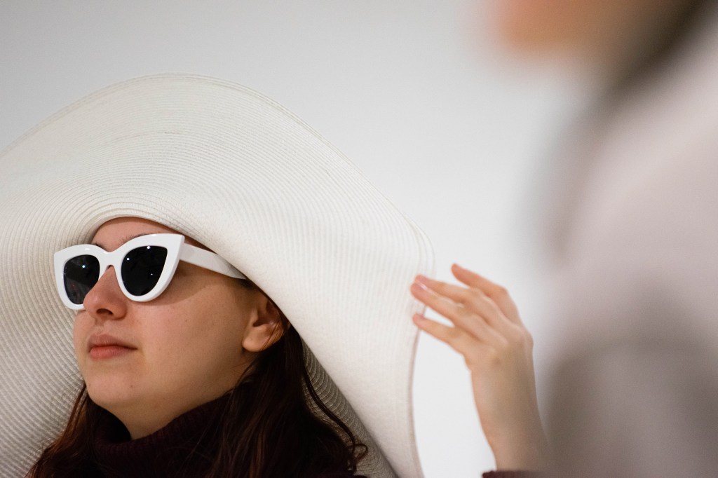 Allie Jeffay wears a large, white sun hat and sunglasses.