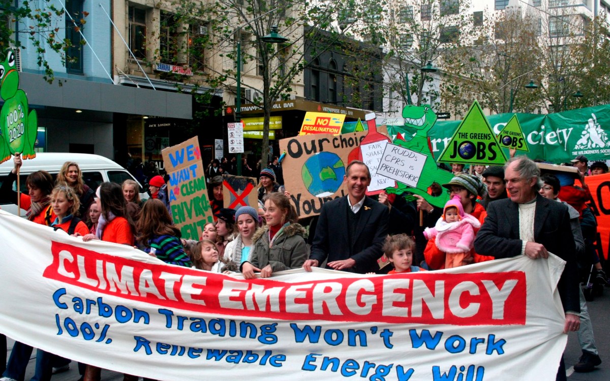 Protestors marching, holding a large banner and signs.