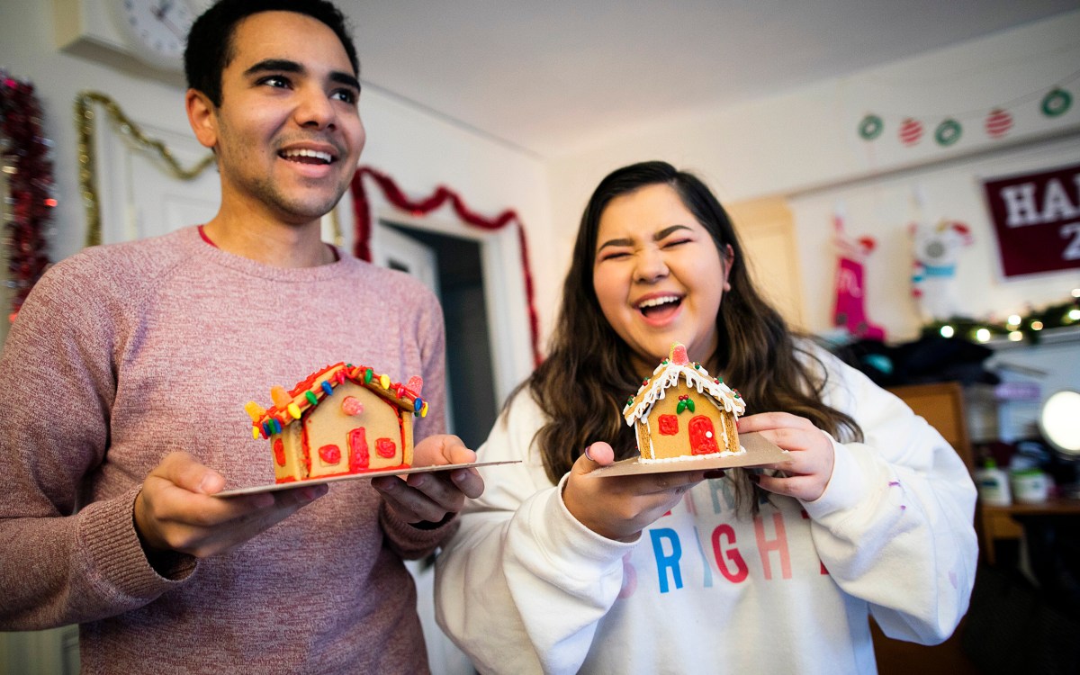 Two students holding gingerbread houses.