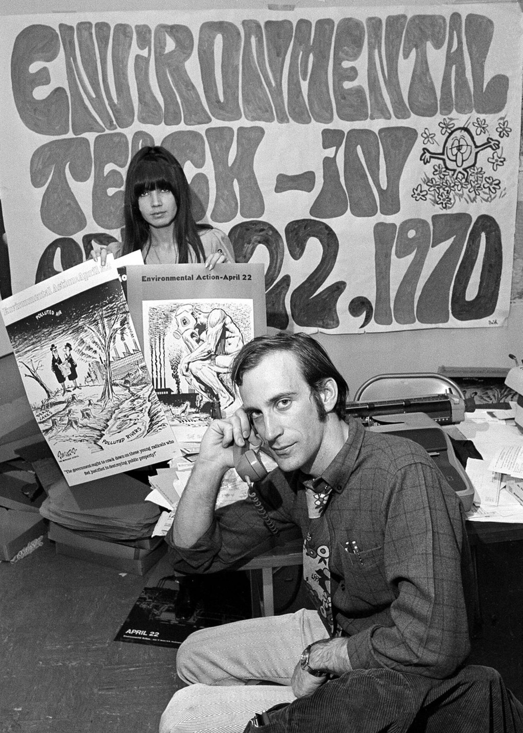 Denis Hayes on phone as associate holds posters advertising Environmental Teach-In in 1970.