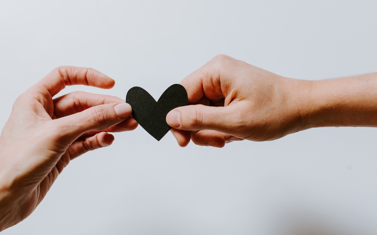 Two hands holding a single paper heart.