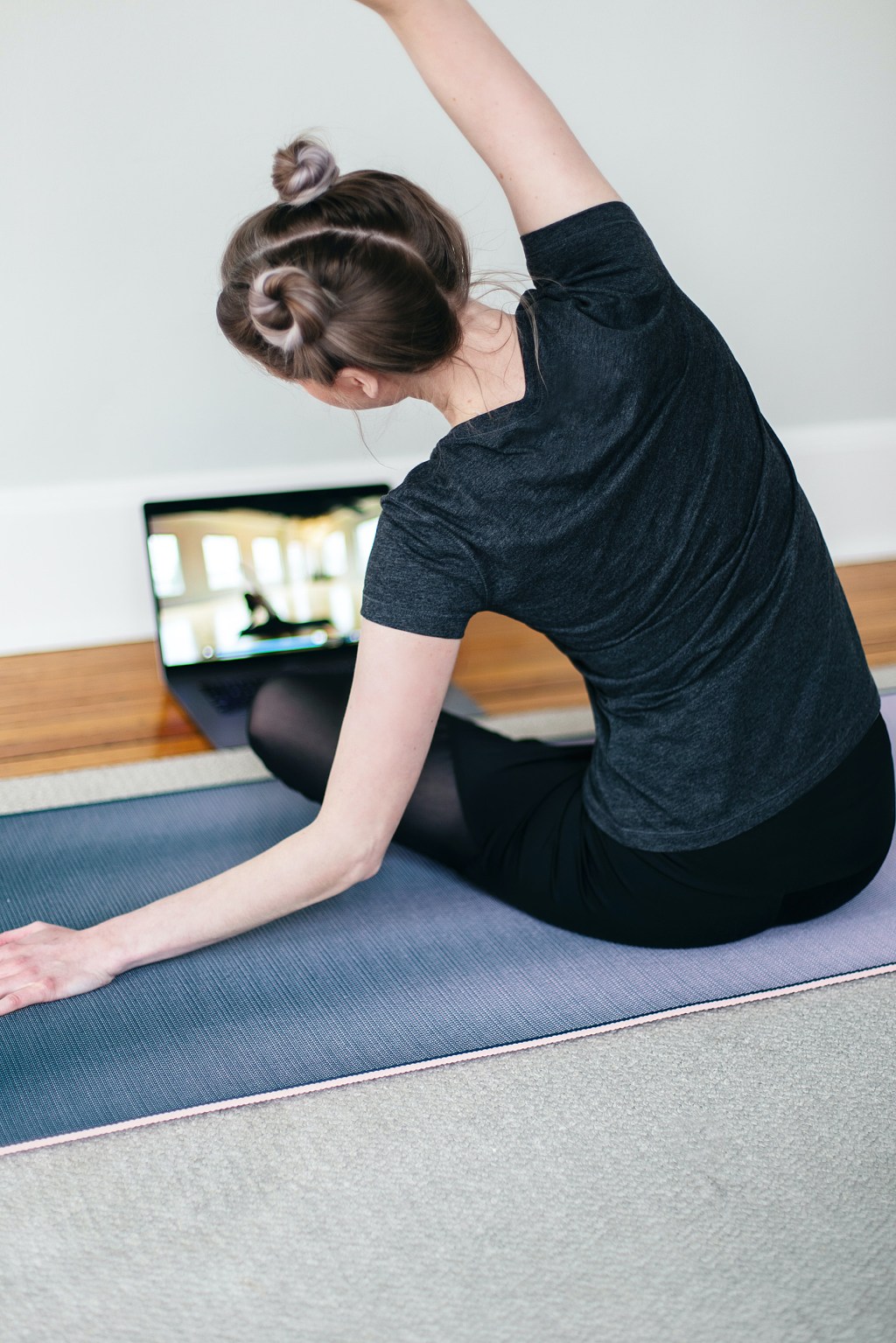 Woman doing yoga in front of laptop.