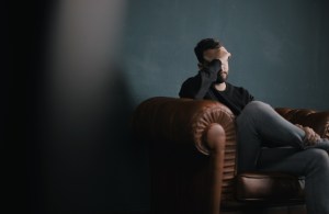 Man sitting on couch looking distressed.