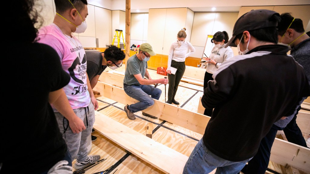 Students gather around instructor Douglas Brooks as they build a Japanese river skiff.