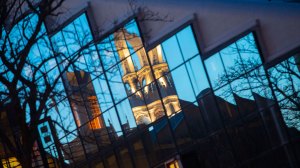 Gund Hall is seen reflecting the tower of Memorial Church at sunset.