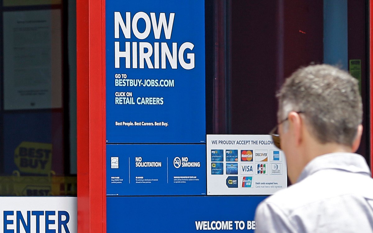 Man looking at "Now Hiring" sign.