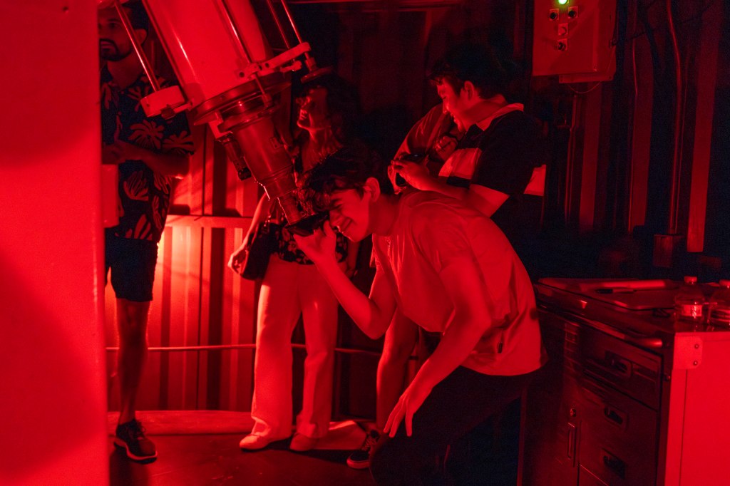 A man looks through a telescope.