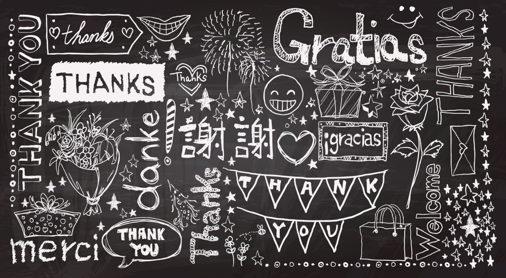 Thank you written in various languages on a chalkboard.