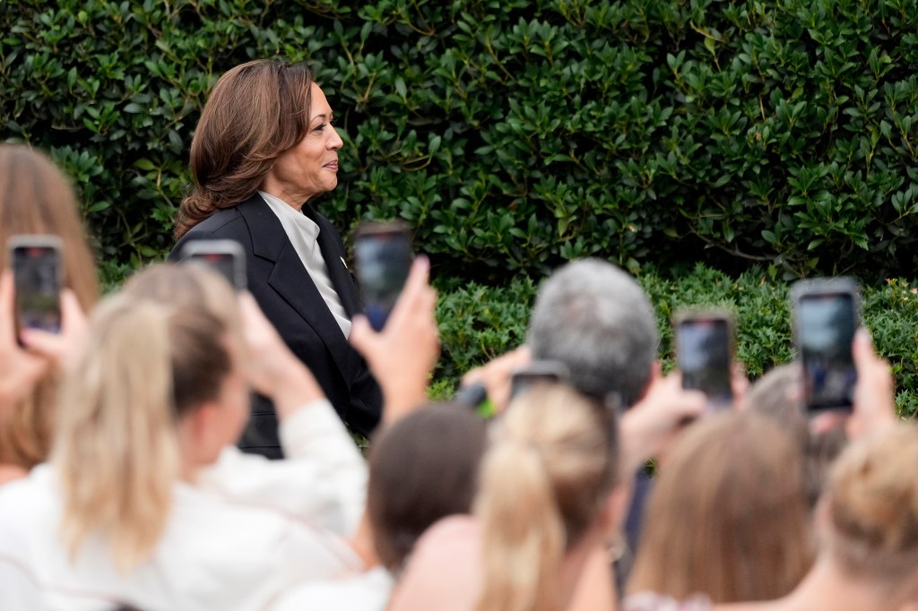 Kamala Harris walks by crowd gathered on White House lawn before speaking at an event.