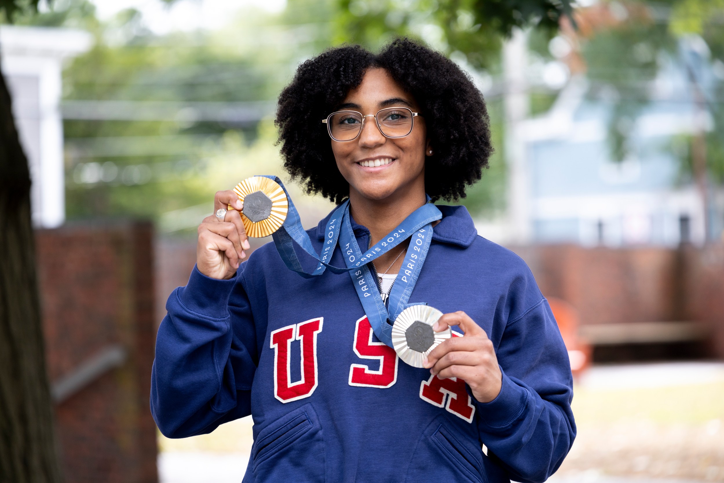 Lauren Scruggs Portrait holding up a silver and gold medal. 