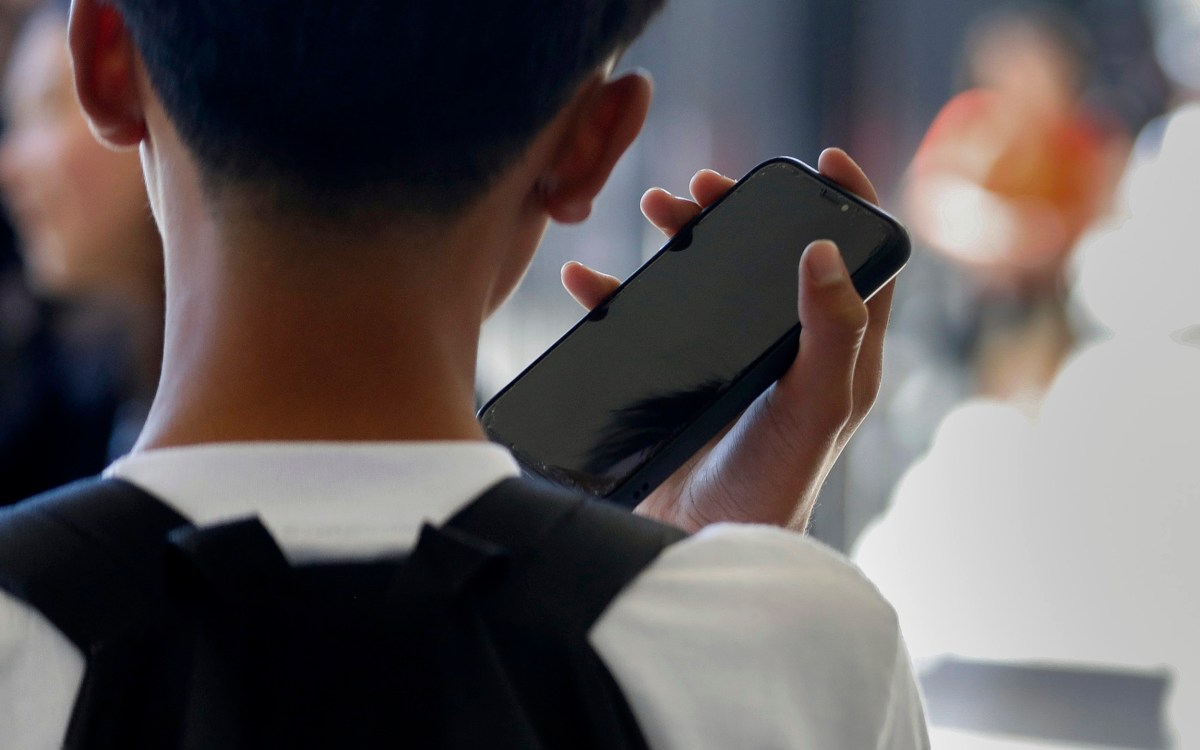 Student uses cellphone in school hallway.