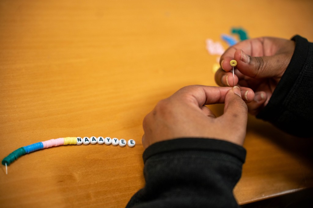 A friendship bracelet-making session shows a student stringing beads. 