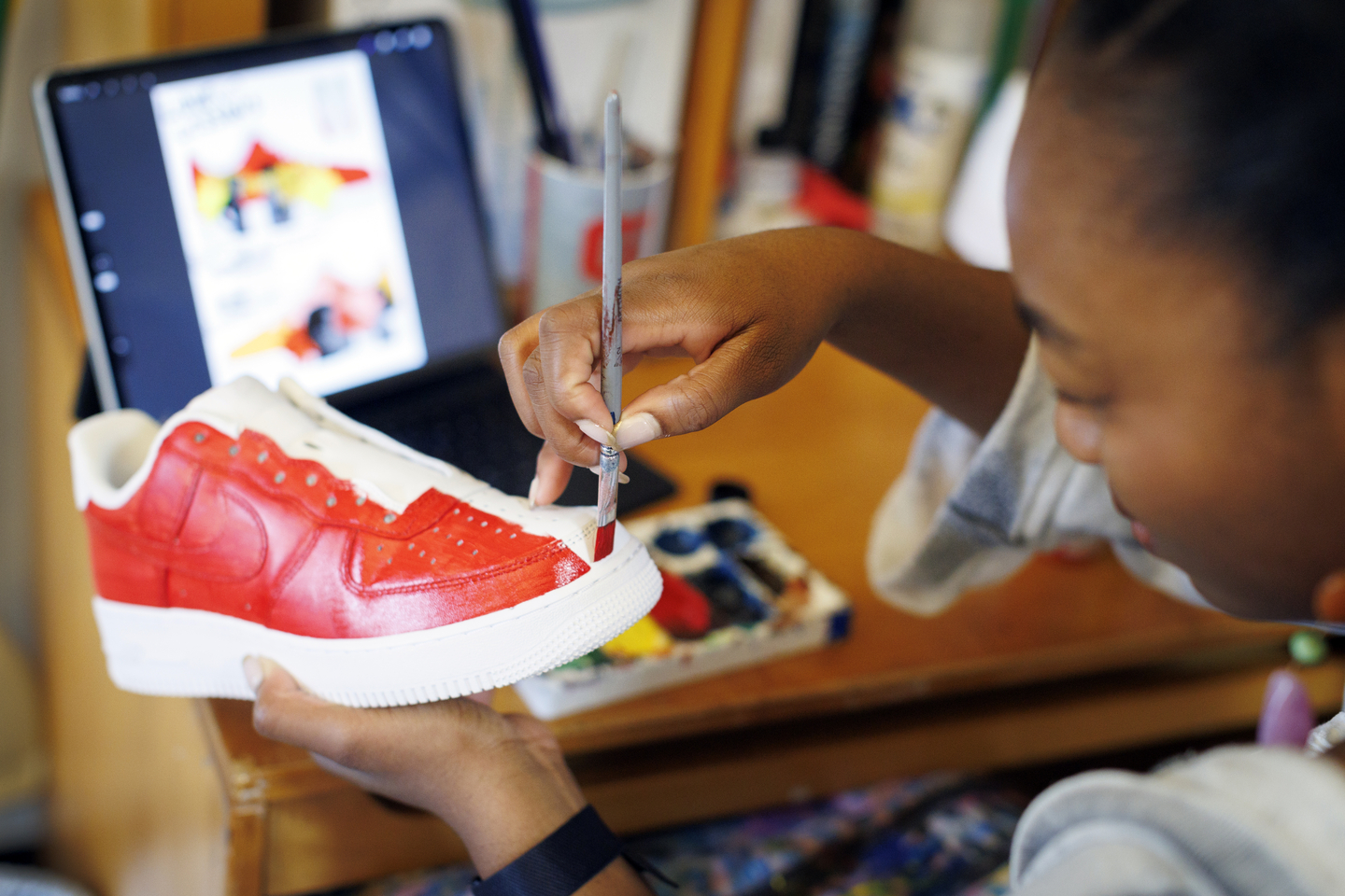 Gabby Anderson painting a pair of shoes. 