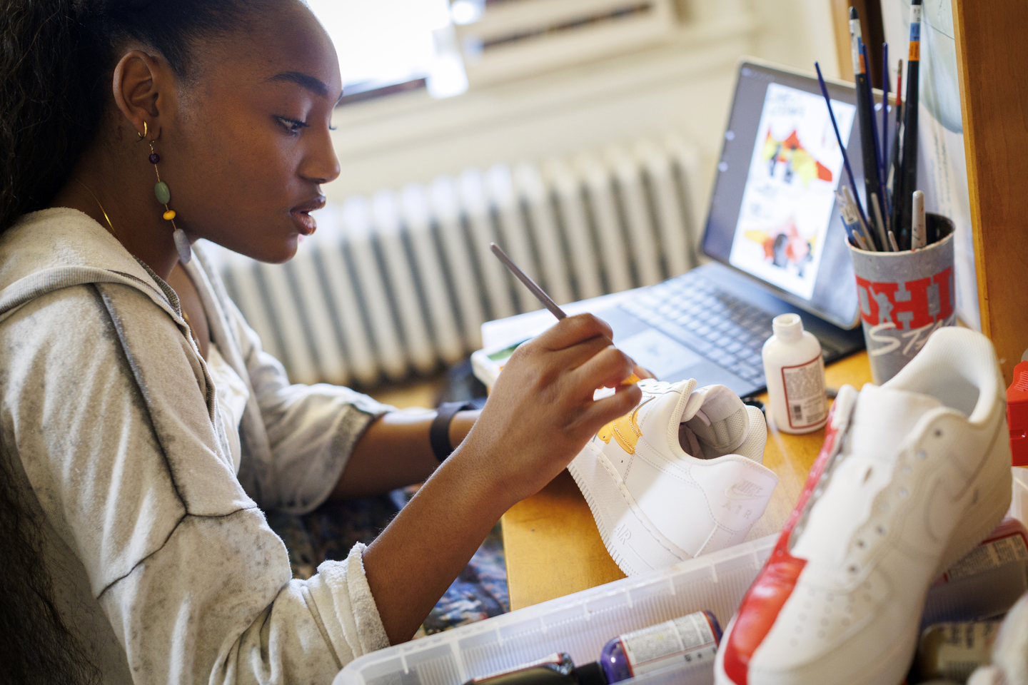 Gabby Anderson painting a pair of shoes. 